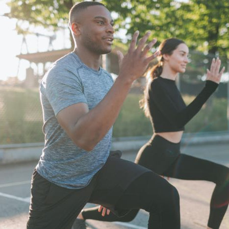 Man and woman exercising outdoors performing lunges
