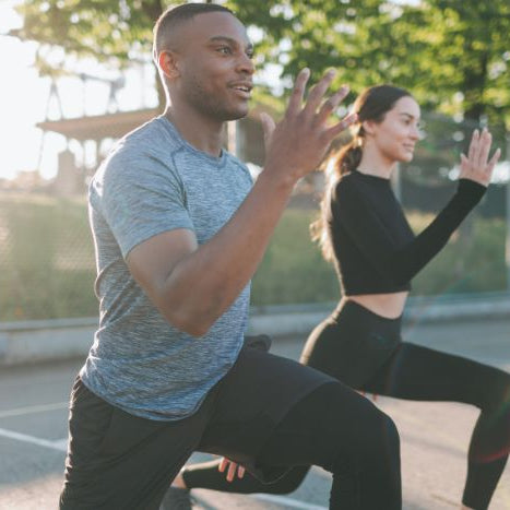 Man and woman exercising outdoors performing lunges