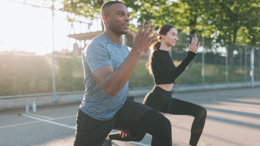 Man and woman exercising outdoors performing lunges