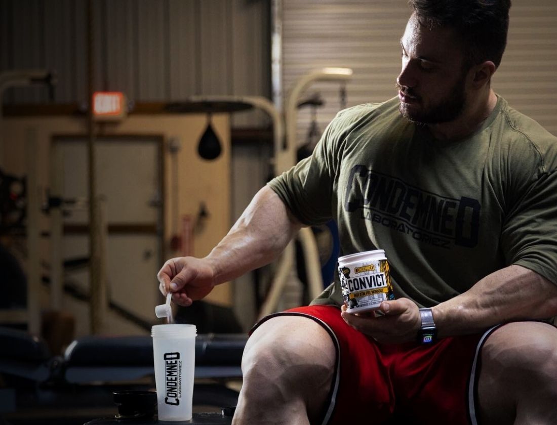 Bodybuilder pouring Condemned Labz Convict pre workout into shaker cup